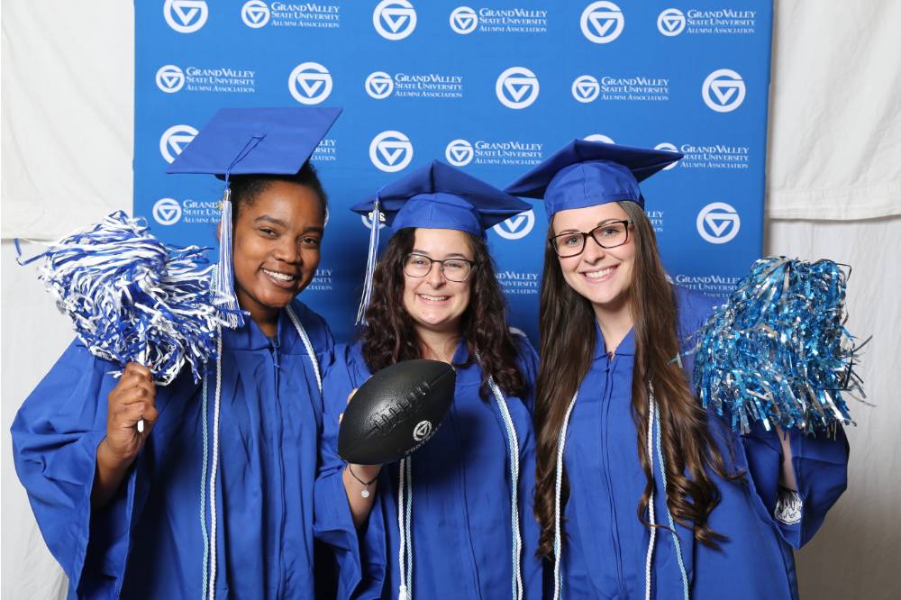 Three upcoming graduates pose with props at GradFest